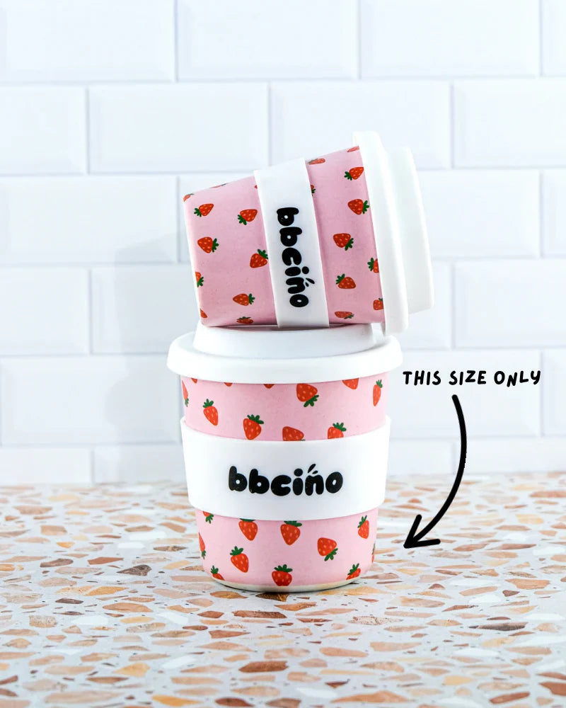 Set of reusable bamboo kids’ cups in different sizes with light pink background and strawberry print, ideal for milkshakes, juices, or hot drinks