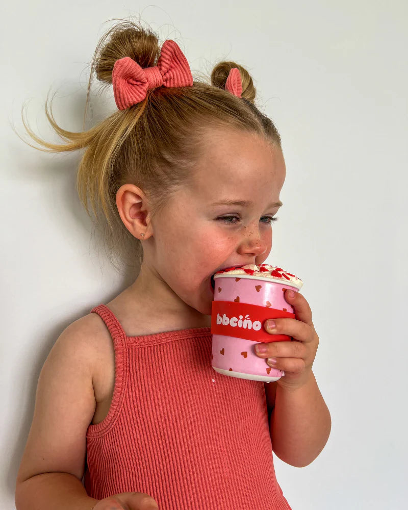 Child drinking from reusable bamboo keep cup with light pink background and strawberry print, sized for little hands