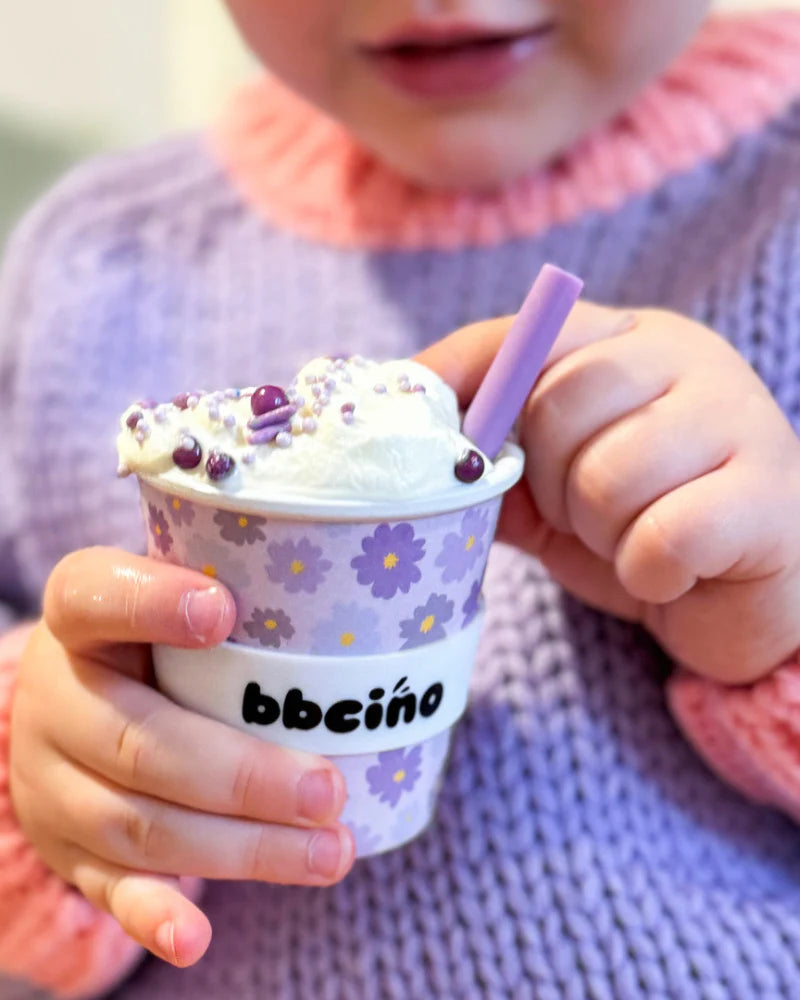 Close-up of toddler holding 120ml BBCino reusable cup with purple flowers and sipping happily.