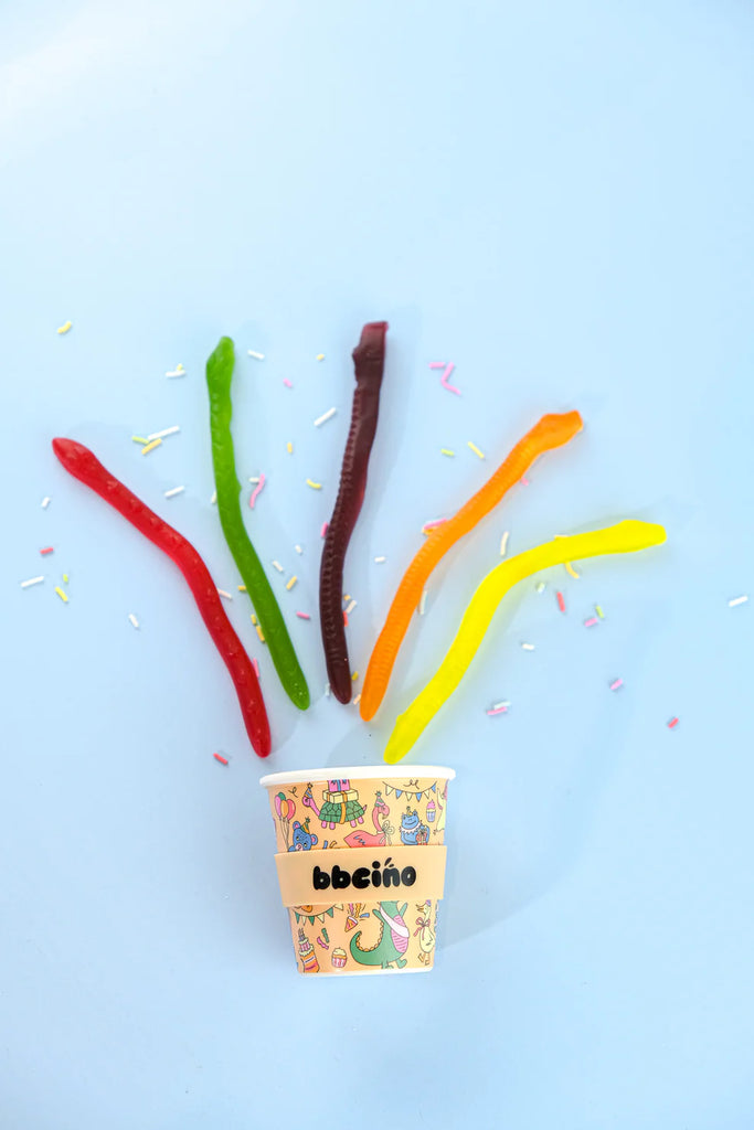 BBCino Party Animal reusable bamboo cup 120ml in orange design, styled with colourful gummy worms and sprinkles on blue background.