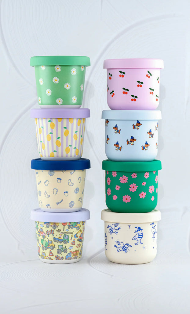 Stack of BBCino bamboo reusable snack pots in assorted prints including Brunch-Kins with navy lid, eco-friendly sustainable snack containers.