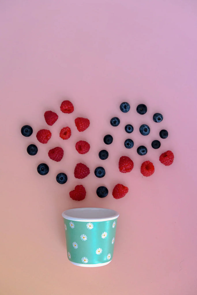BBCino reusable bamboo snack pot in Daisy BB daisy design, styled with fresh raspberries and blueberries on pink background, sustainable kids’ lunchbox container.