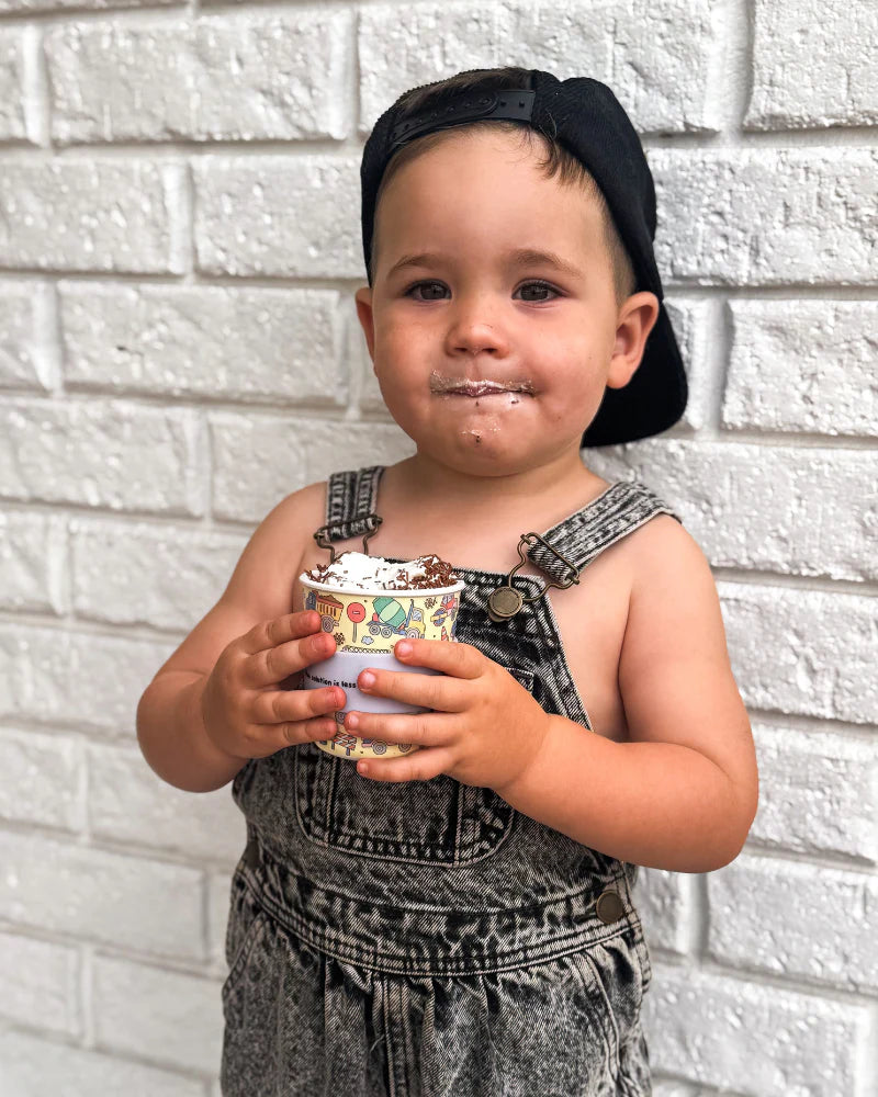 Smiling child holding a BBCino 240ml truck print reusable cup, ideal for smoothies, juices, and milkshakes.