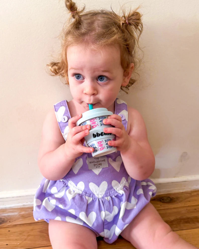 Toddler in purple playsuit drinking from BBCino Ashleigh Fish 120ml cup with matching straw