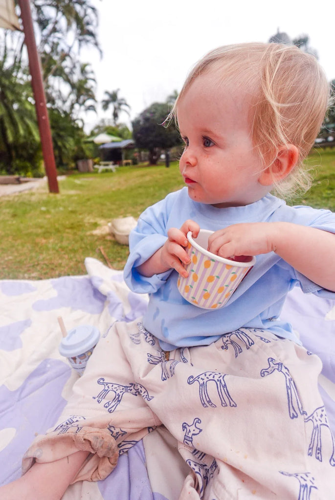 Toddler enjoying snacks from a BBCino reusable bamboo snack pot with lemon design and lilac lid, eco-friendly alternative to plastic lunchbox containers.