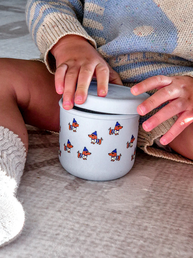 Child opening BBCino reusable silicone snack pot in Dagwood dachshund dog design, 250ml unbreakable and leak-resistant food container.