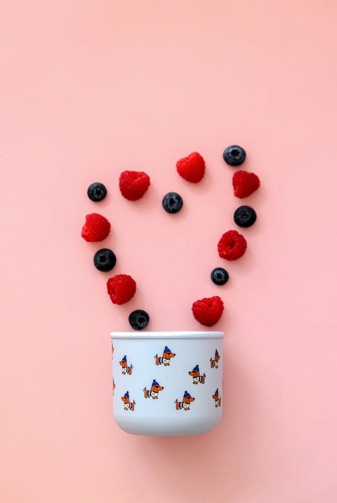 BBCino Dagwood silicone snack pot with dachshund print, styled with fresh raspberries and blueberries in heart shape, reusable snack container.
