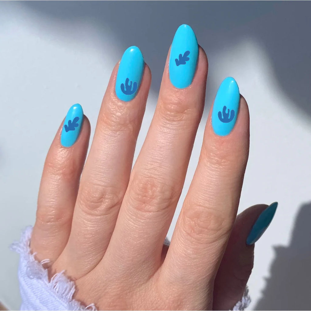 Hand with blue nail polish and leaf design on a light background