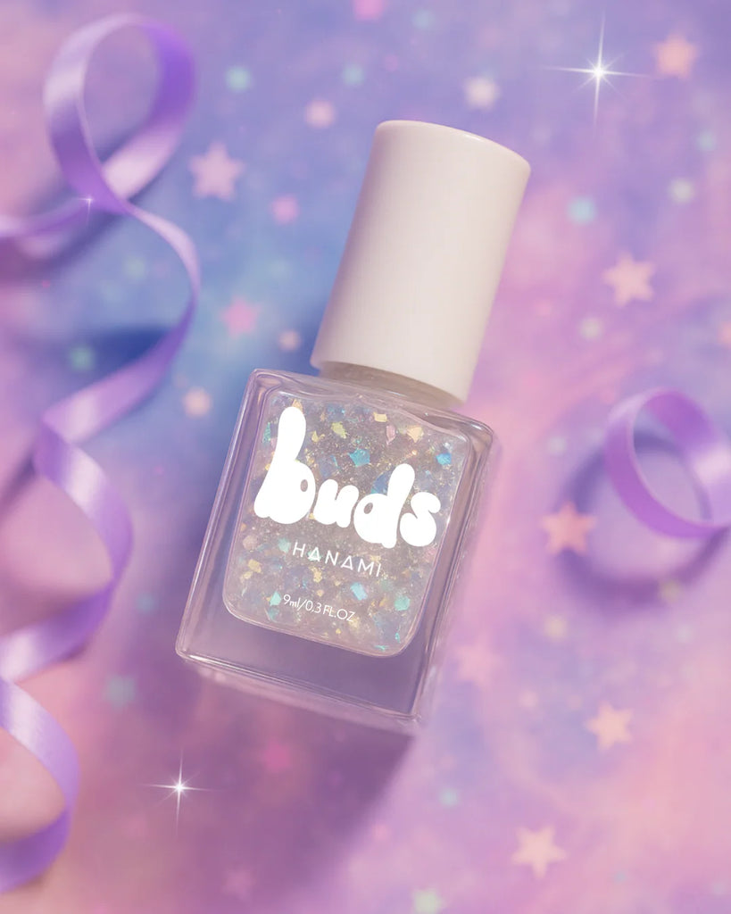 A bottle of Buds Hanami nail polish with iridescent glitter sits on a dreamy pastel background with purple ribbon and star accents.