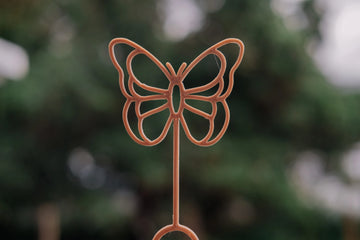 Close-up of Kinfolk Pantry Butterfly Eco Bubble Wand outdoors, crafted from recycled sawdust and PLA bioplastic.