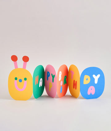Folded caterpillar birthday card with cheerful bug face and colourful letters spelling "HAPPY BIRTHDAY" across bright segments.