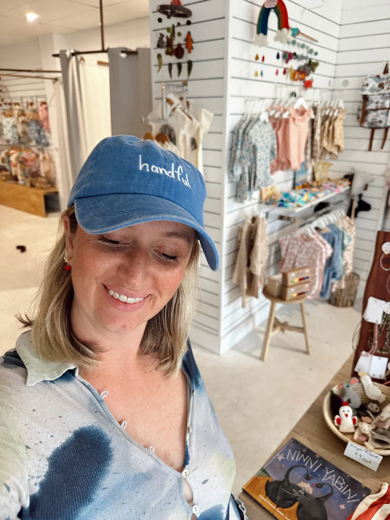 Close-up of smiling woman in the cobalt blue "Handful" cap, highlighting the cheerful, fun vibe of this embroidered adult accessory.