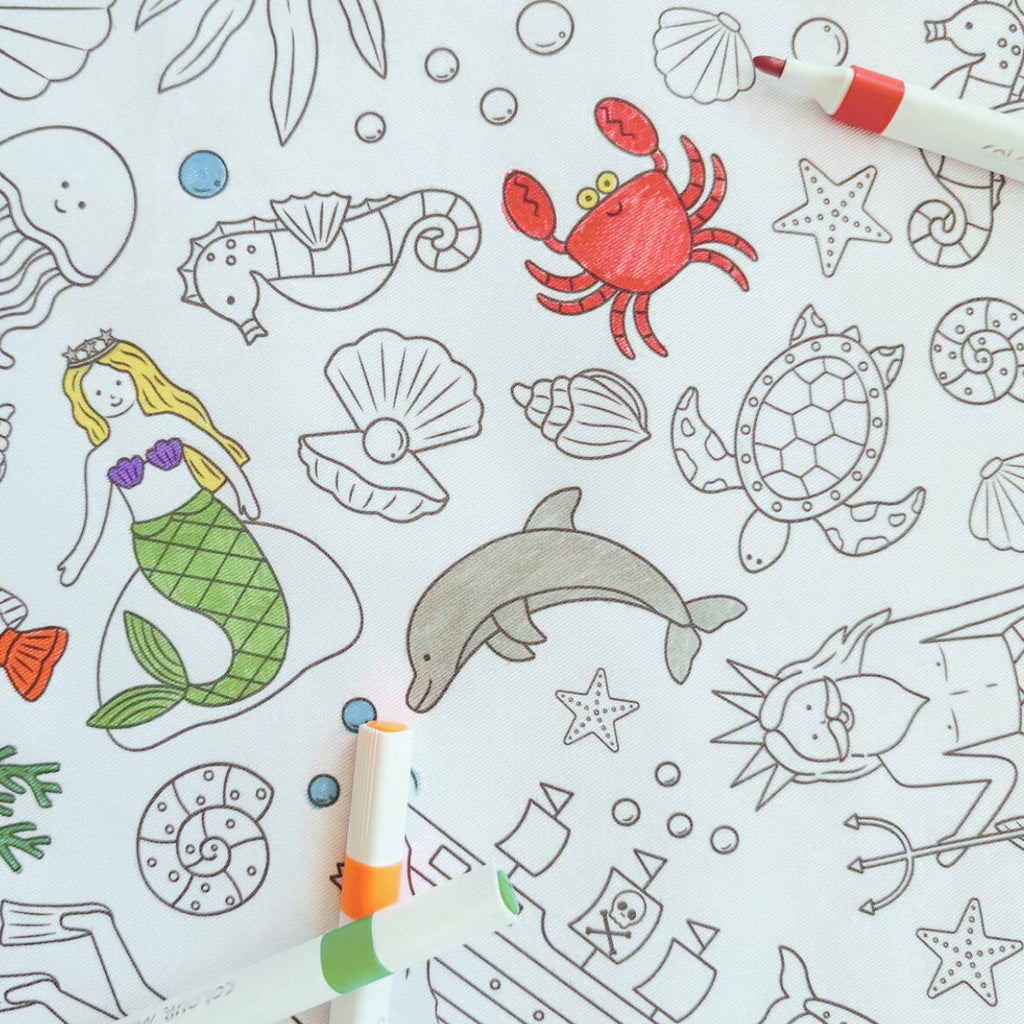 Close-up of the Tidal Treasures reusable tablecloth showing outlined sea creatures like turtles, fish, dolphins, coral and shells ready to be coloured in.
