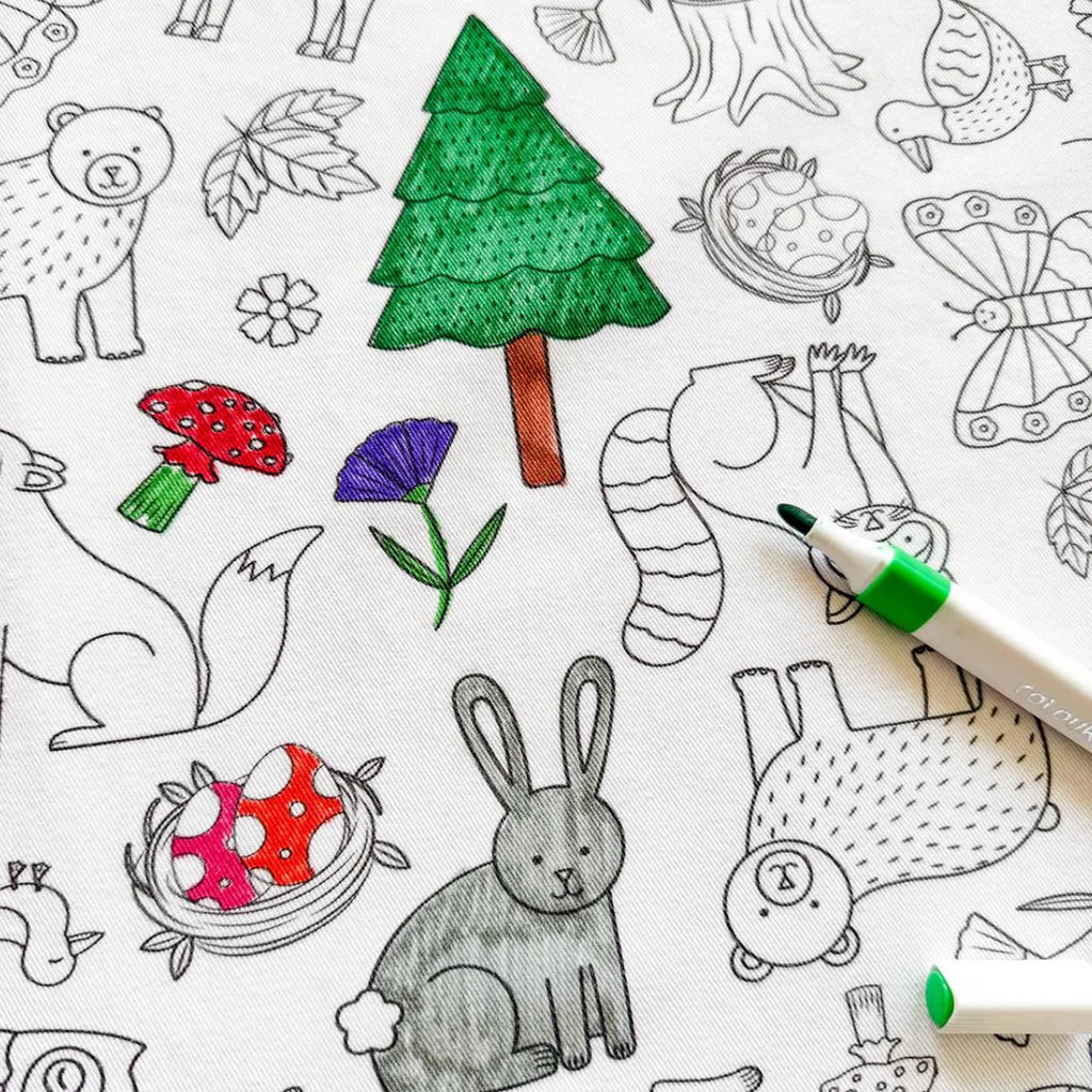 Section of the Woodland Wonders tablecloth partially coloured in, highlighting whimsical forest elements like mushrooms, trees, and woodland creatures.