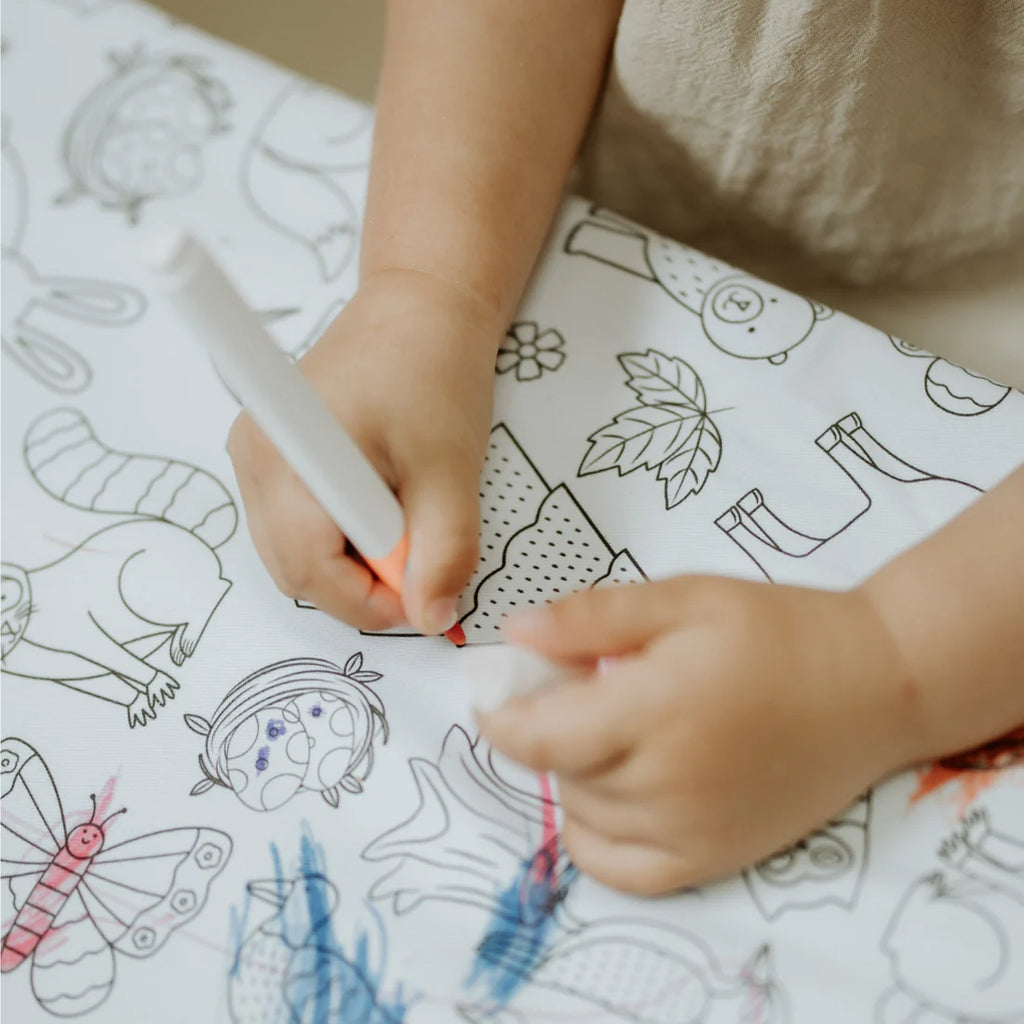 Child using washable markers to colour the Woodland Wonders tablecloth, showing soft cotton surface and playful eco-friendly design.