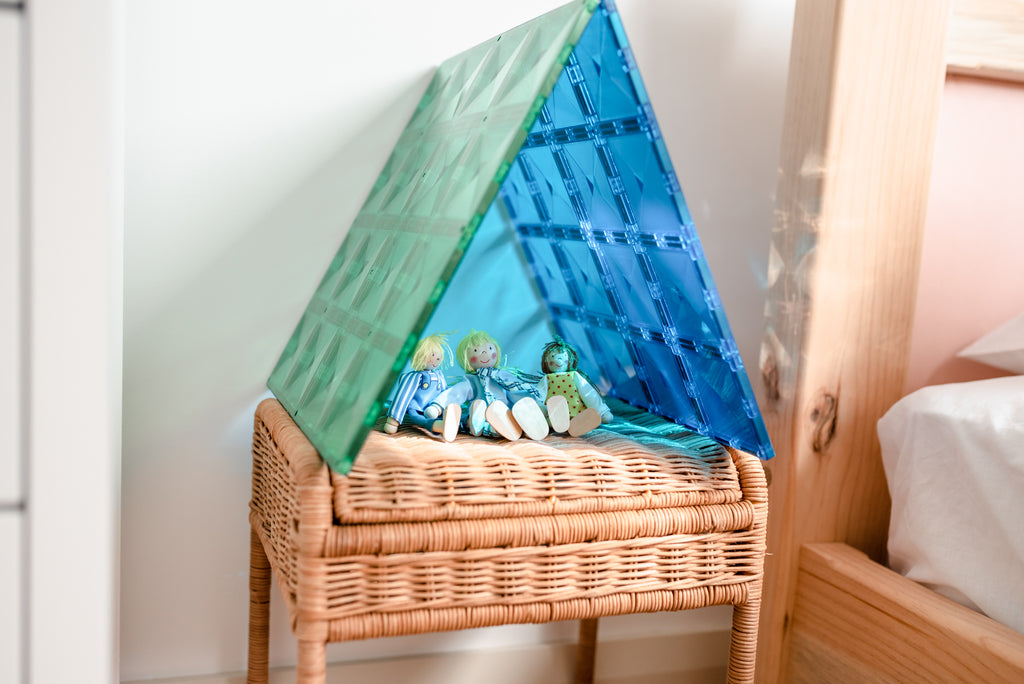 Base plates arranged in a triangle roof shape, placed atop a rattan storage basket in a softly lit bedroom setting.
