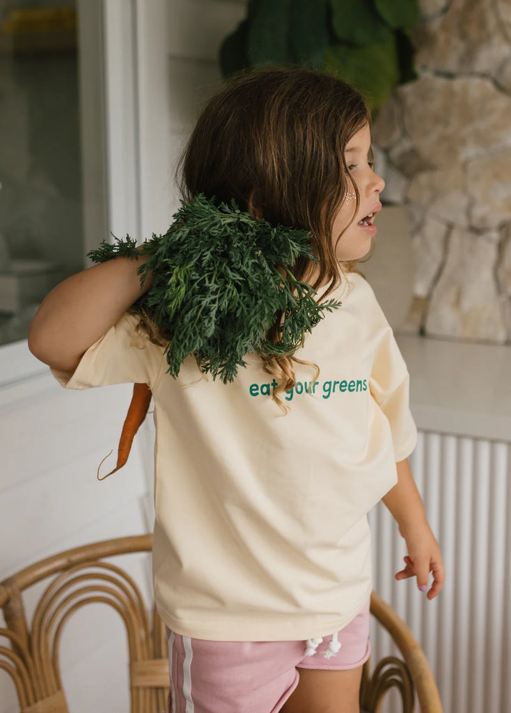 Child wearing the tee with fresh broccoli balanced on their shoulder, adding a cheeky veggie-themed touch that ties perfectly with the slogan and playful tone.