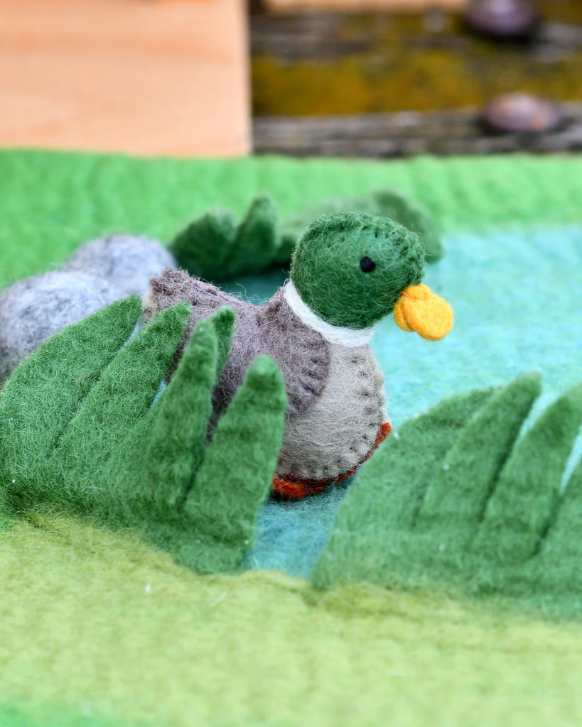 Felt duck toy on a textured green felt play mat, surrounded by stitched ripples for a pond-themed small world setup.