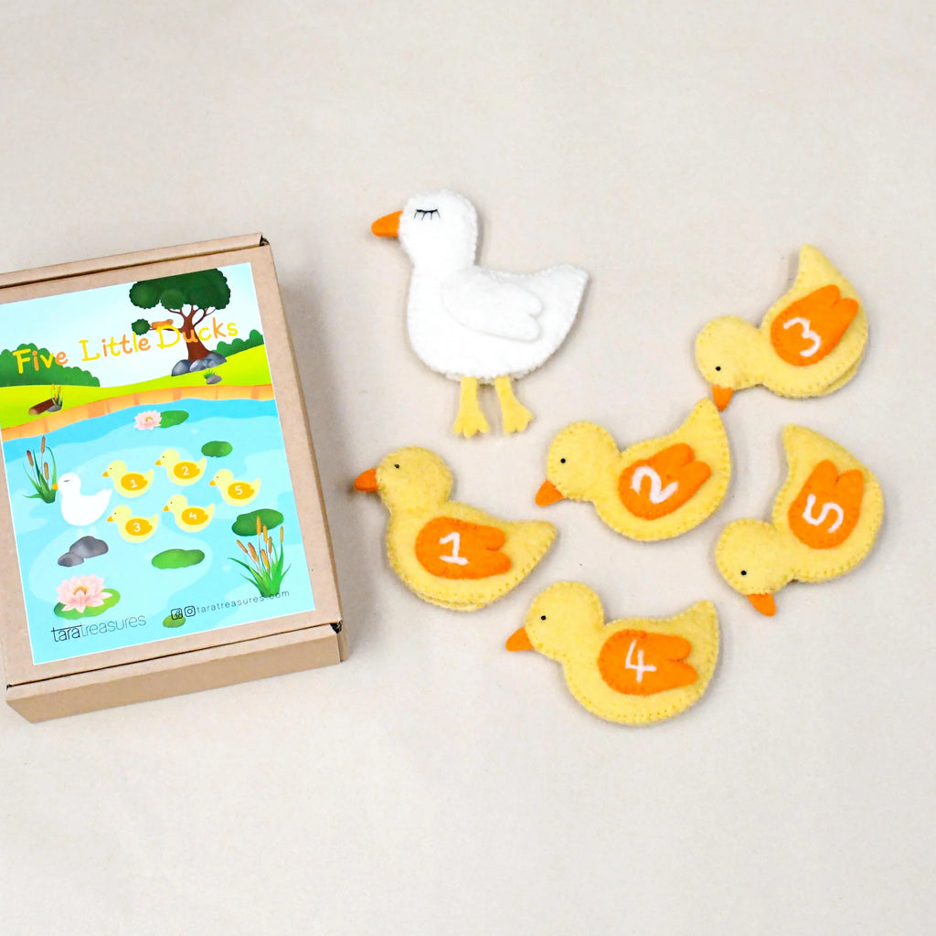 Five yellow duckling puppets and one white mother duck arranged beside a themed box on a light background.