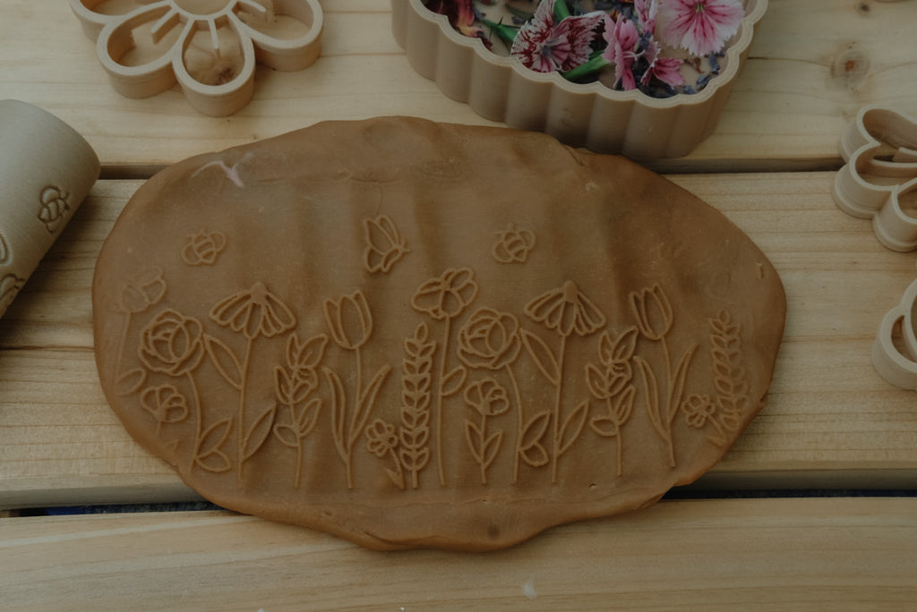 Detailed floral impressions in terracotta playdough made using the Kinfolk Pantry Flower Playdough Roller, styled with dried petals.