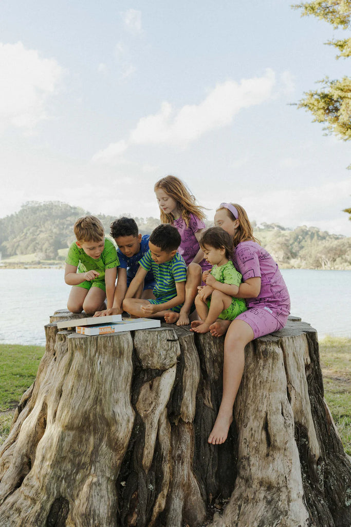 Children sitting on a large tree stump by a lake