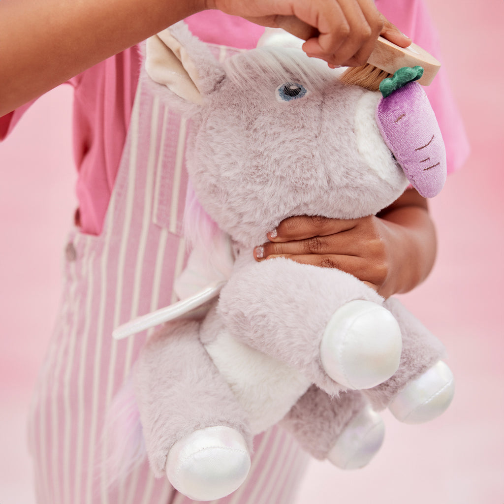 Close-up of child holding Glimmer unicorn – Showing silver hooves, rainbow mane, and lavender wings in detail.