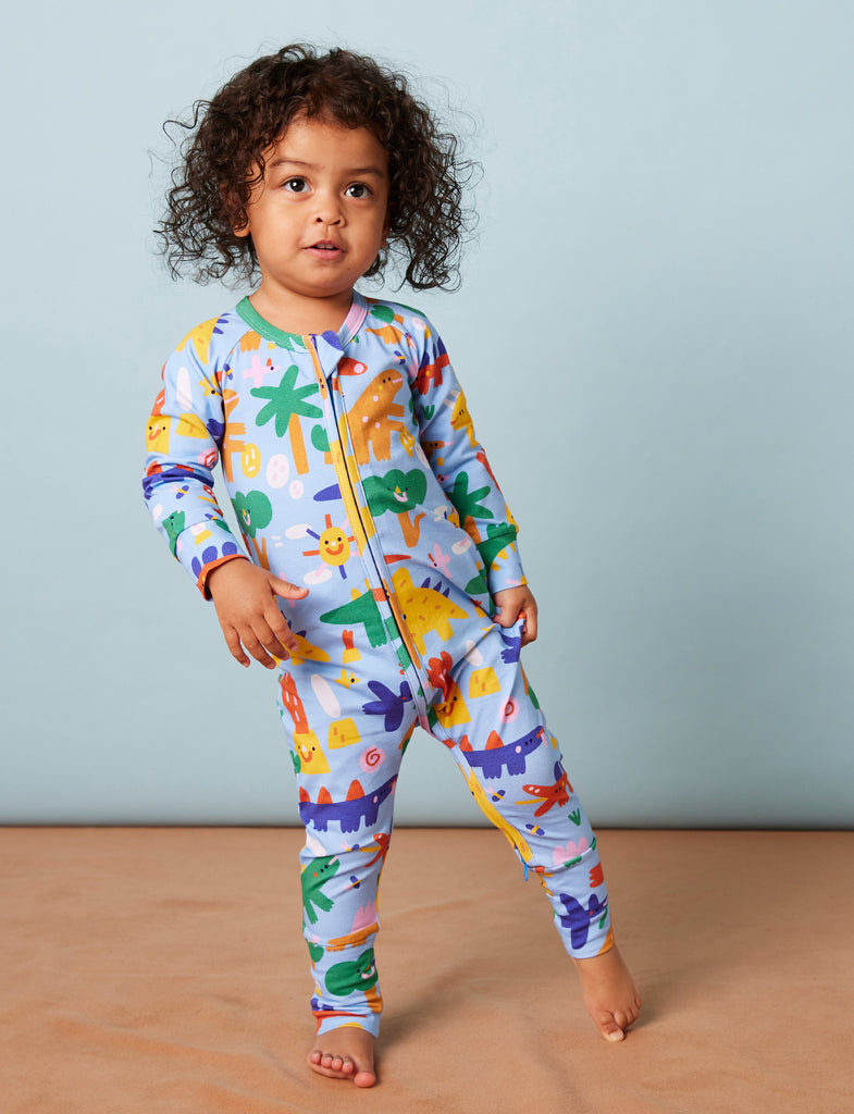 Toddler wearing the Dino Days romper by Halcyon Nights, showing vibrant multicoloured dinosaur print and relaxed fit in a standing pose.