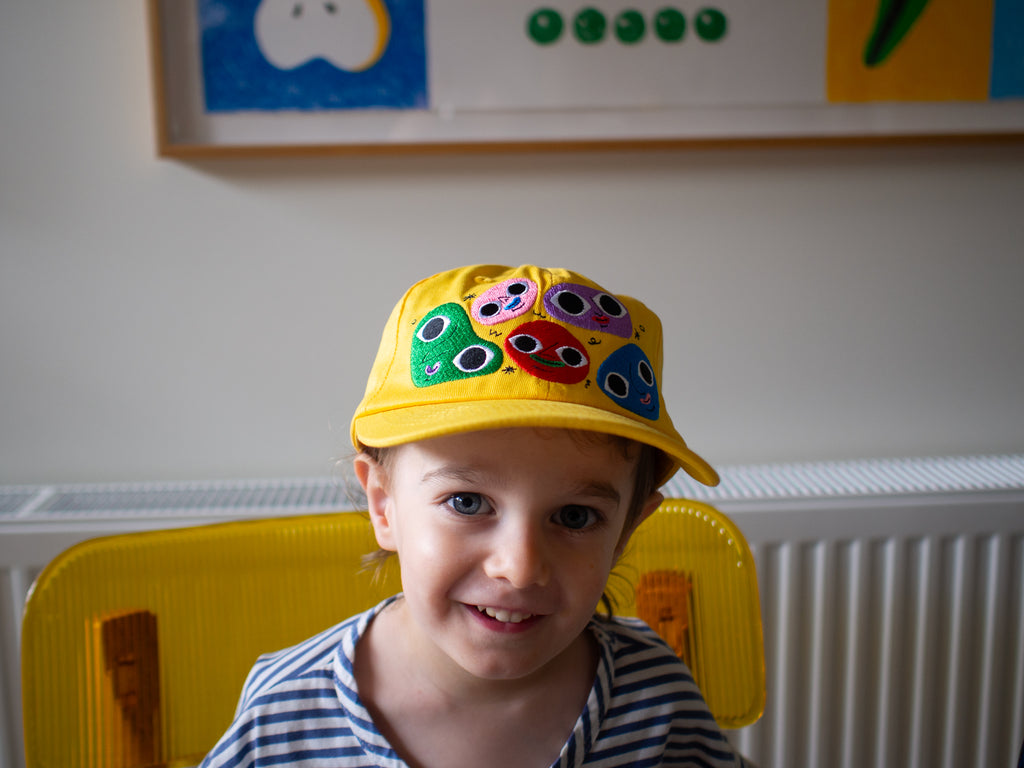 Cheerful yellow cotton twill cap, the Happy Chap Cap, designed by Melbourne illustrator Samantha Curcio. Features playful embroidered details, perfect for kids aged 2+.