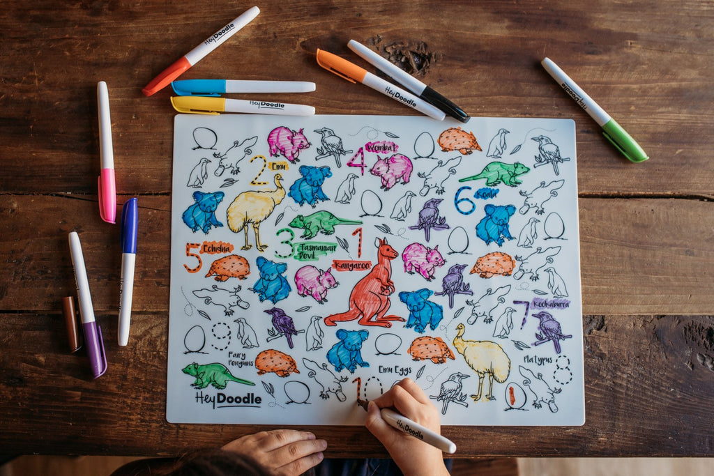 Child colouring Australian animals on the HeyDoodle Aussie Animals mat with colourful markers.