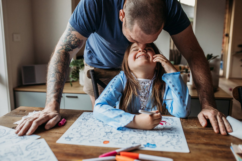 Father helping daughter colour the Aussie Animals activity mat at the table.