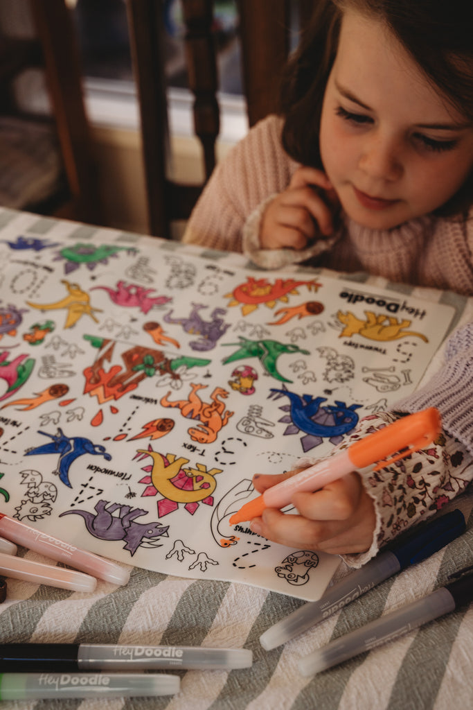 Child coloring with markers on a HeyDoodle DinoRoar Silicone Colouring Mat