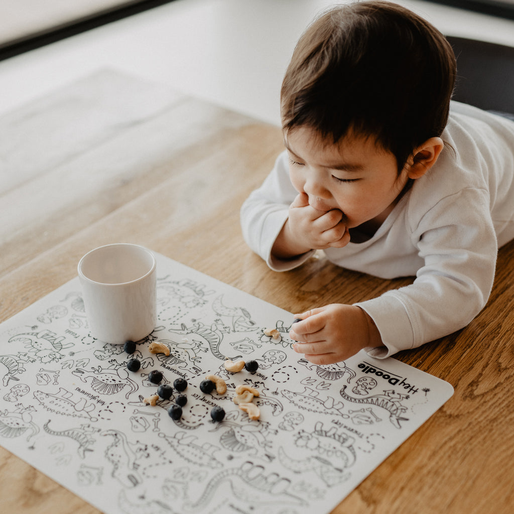 Child using the HeyDoodle Colouring Mat a a placemat with Blueberries and cashews.