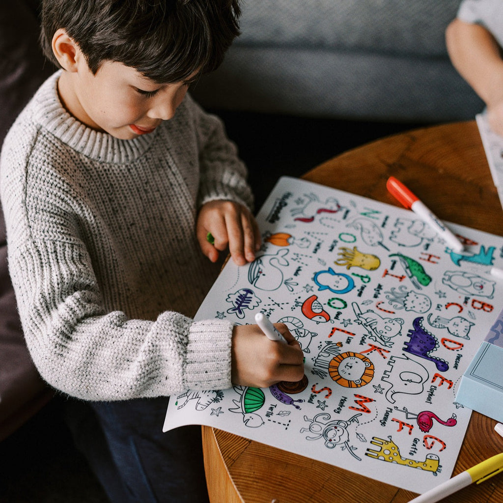 Child engaged in colouring the Into the Wild mat at a table, exploring the reusable silicone surface.