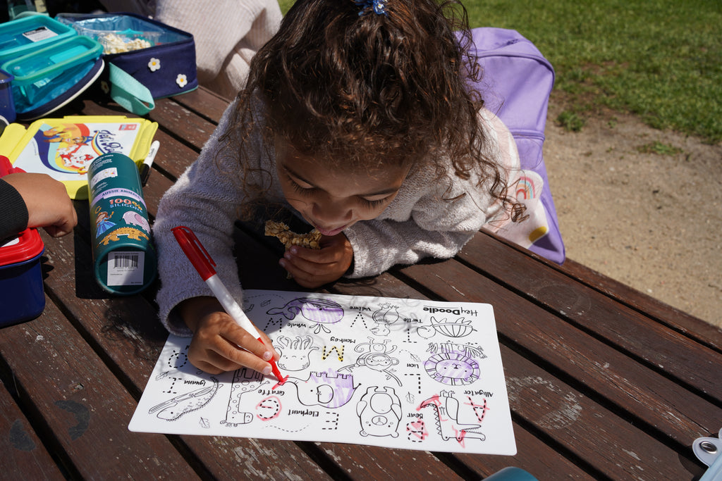 Overhead view of HeyDoodle mat being coloured by child in natural sunlight.