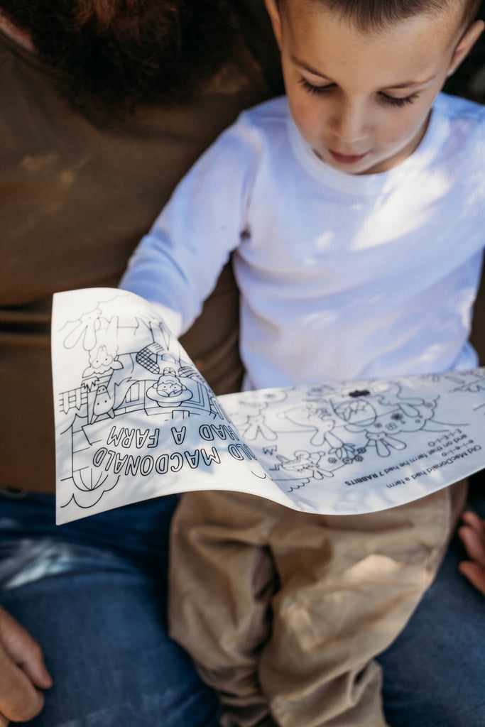 Child sitting with parent reading the HeyDoodle Old MacDonald silicone book.