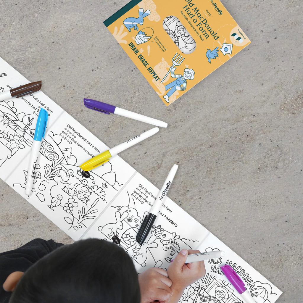 Child tracing farm animals in the extended Old MacDonald silicone book layout.