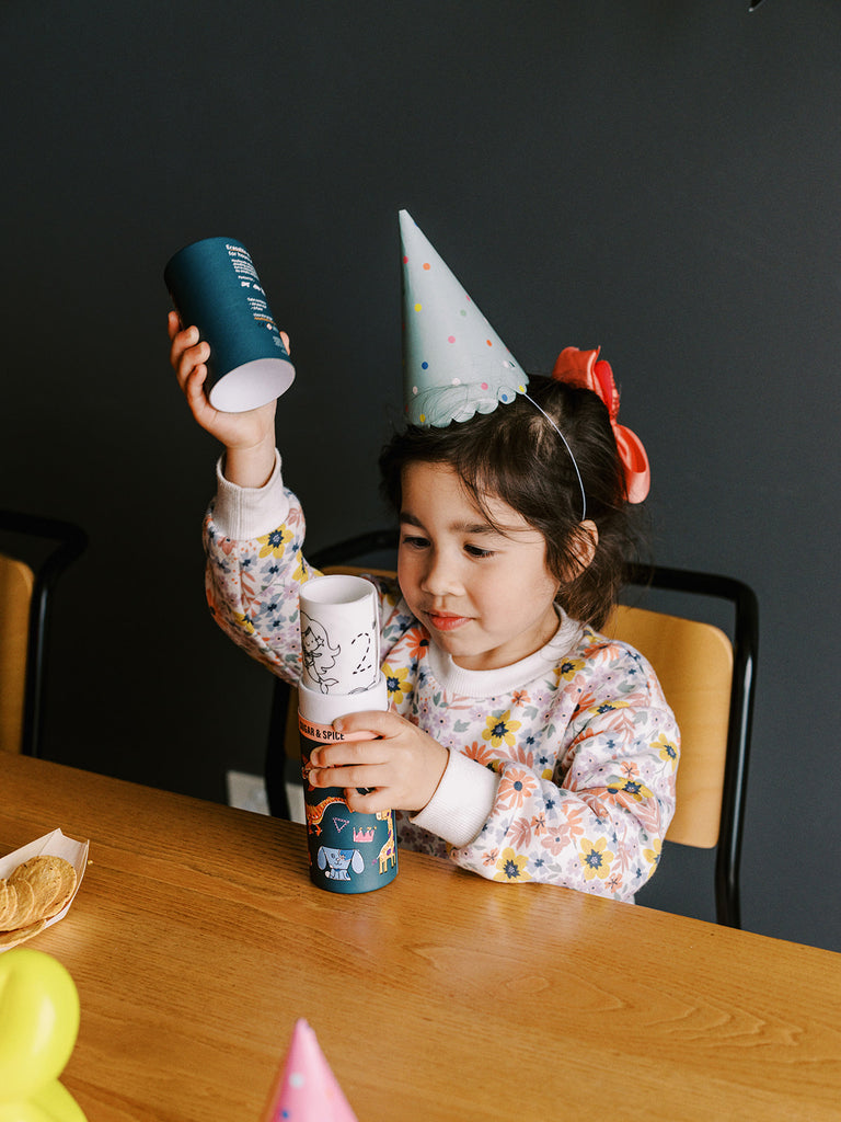 Child engaged in colouring the Sugar & Spice HeyDoodle mat using markers, with a cupcake on the table.
