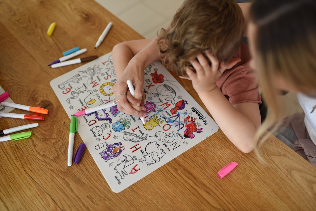  Parent and child colouring the reusable transportation-themed mat together.