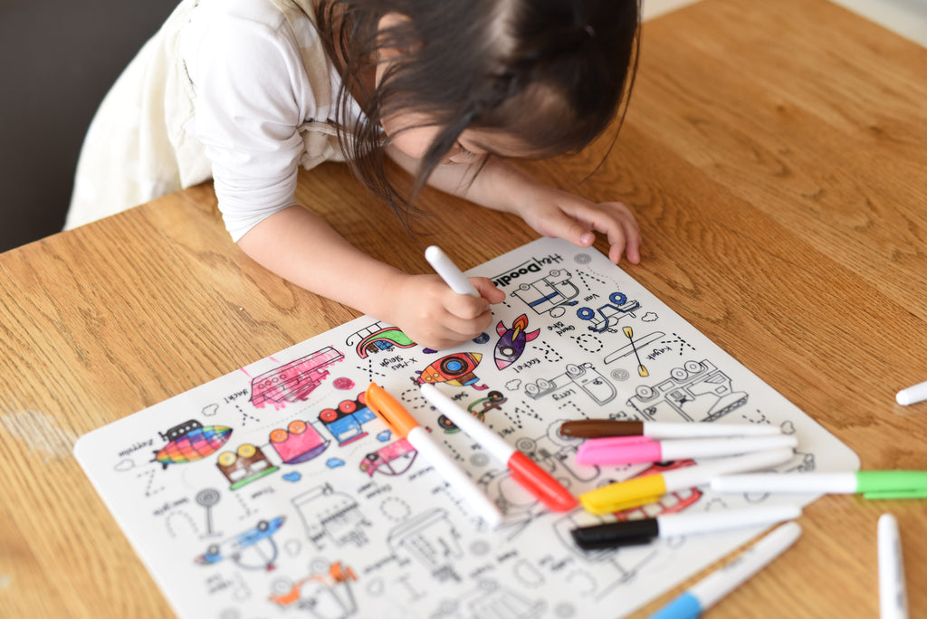 Close-up of child colouring different vehicles on the Toot Toot Honk silicone mat with markers.