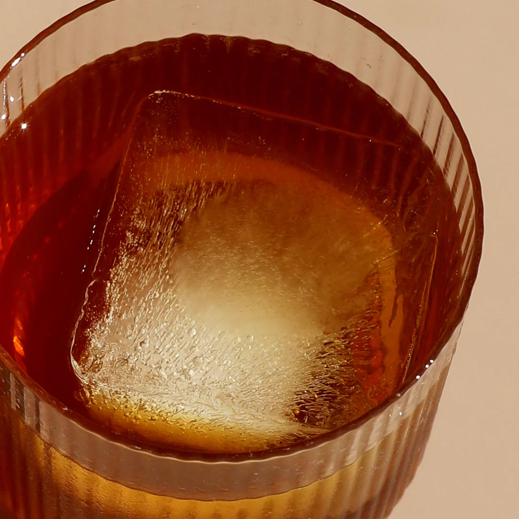 Hydramama Cola - Hydration Electrolyte Drink for Pregnancy & Postpartum - Hydramama drink in glass with one large ice cube.