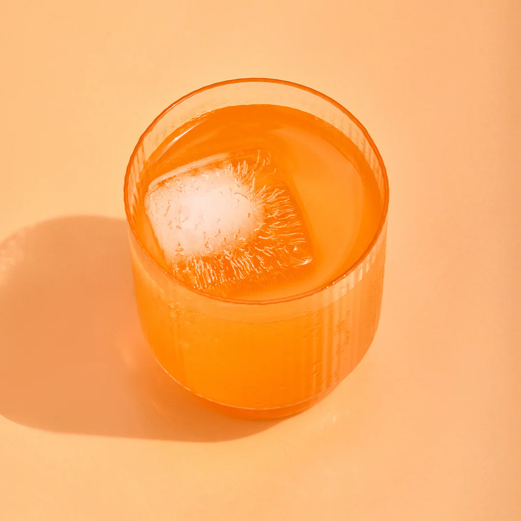Hydramama Passionfruit & Orange Hydration Electrolyte Drink for Pregnancy & Postpartum - Hydramama in a glass with an ice cube.