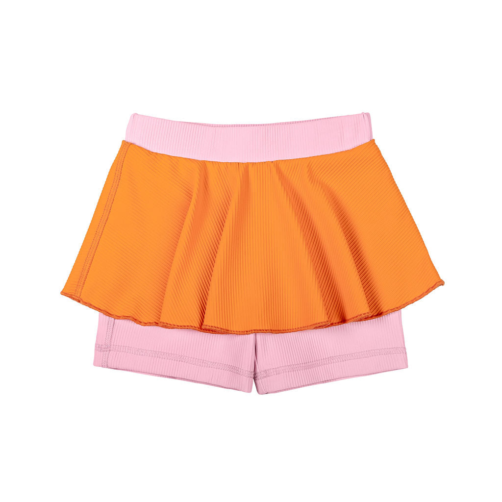 Bubblegum swim skort with tangerine ribbed shorts and a light pink skirt overlay, featuring UPF 50+ protection and a beige lining. Fun and flouncy design, perfect for sunny beach or pool days.