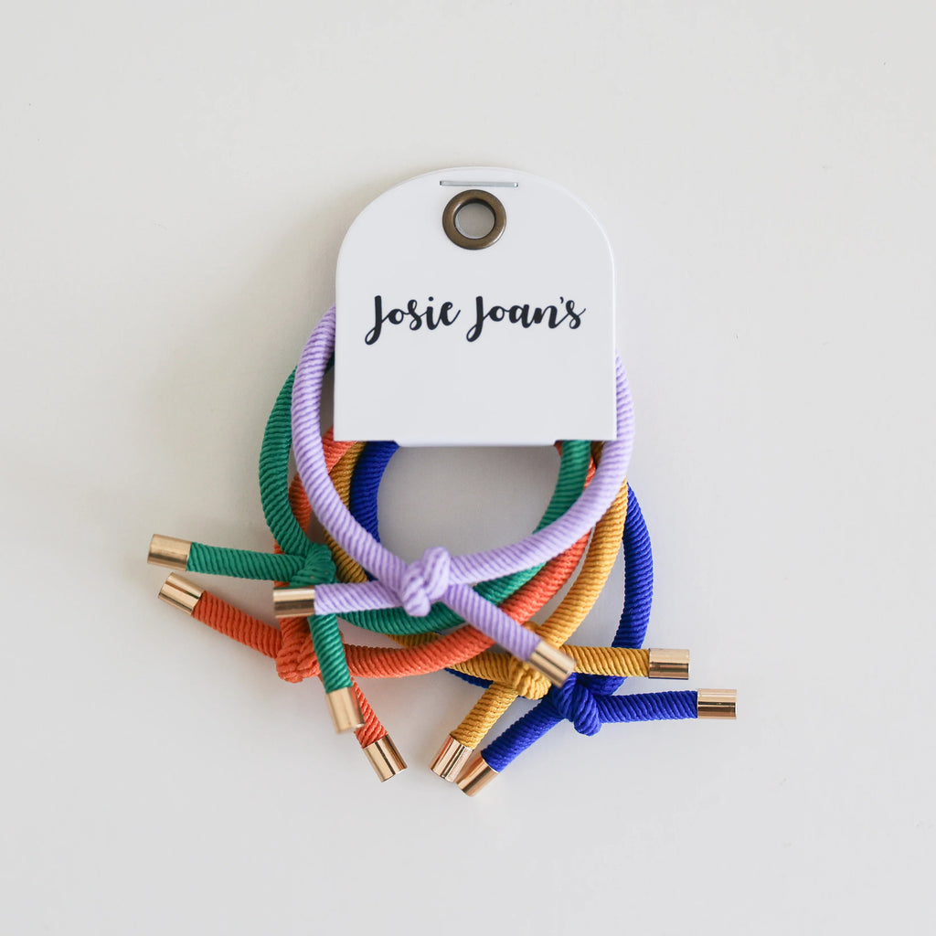 Colorful hair ties with gold ends on a white background, featuring a 'Josie Joan's' tag.