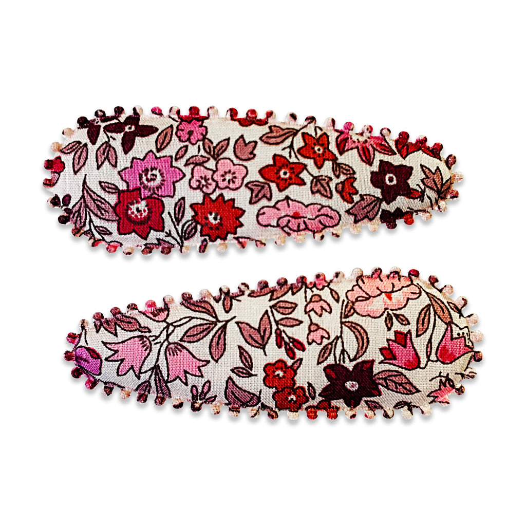 Two fabric-covered snap hair clips with a floral pattern, featuring scalloped edge detail.