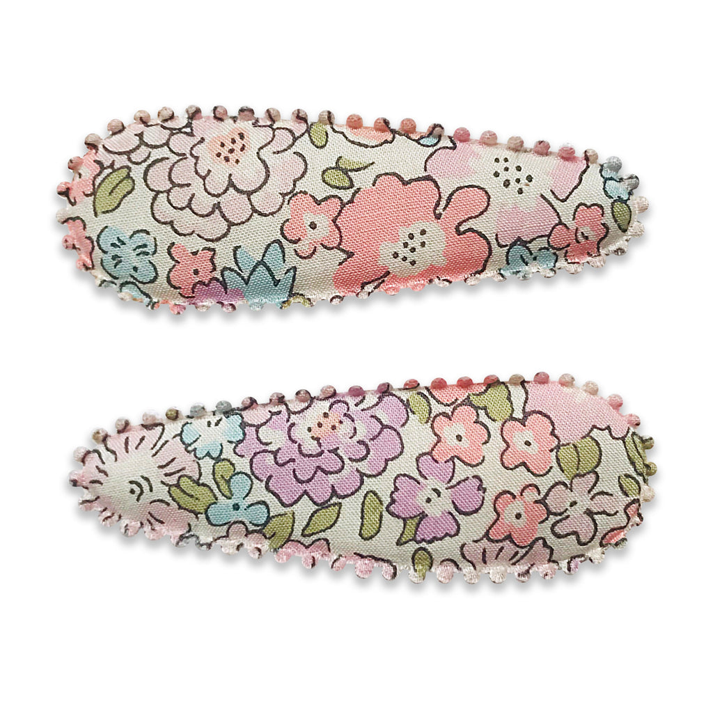 Two fabric-covered snap hair clips with pastel floral Liberty-style prints and scalloped embroidered edges, displayed on a white background.