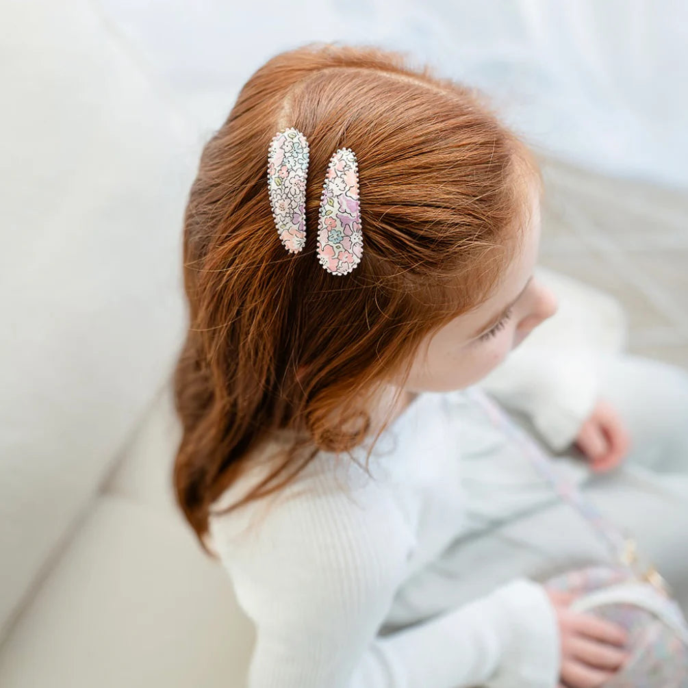 Child with red hair wearing decorative hair clips against a neutral background