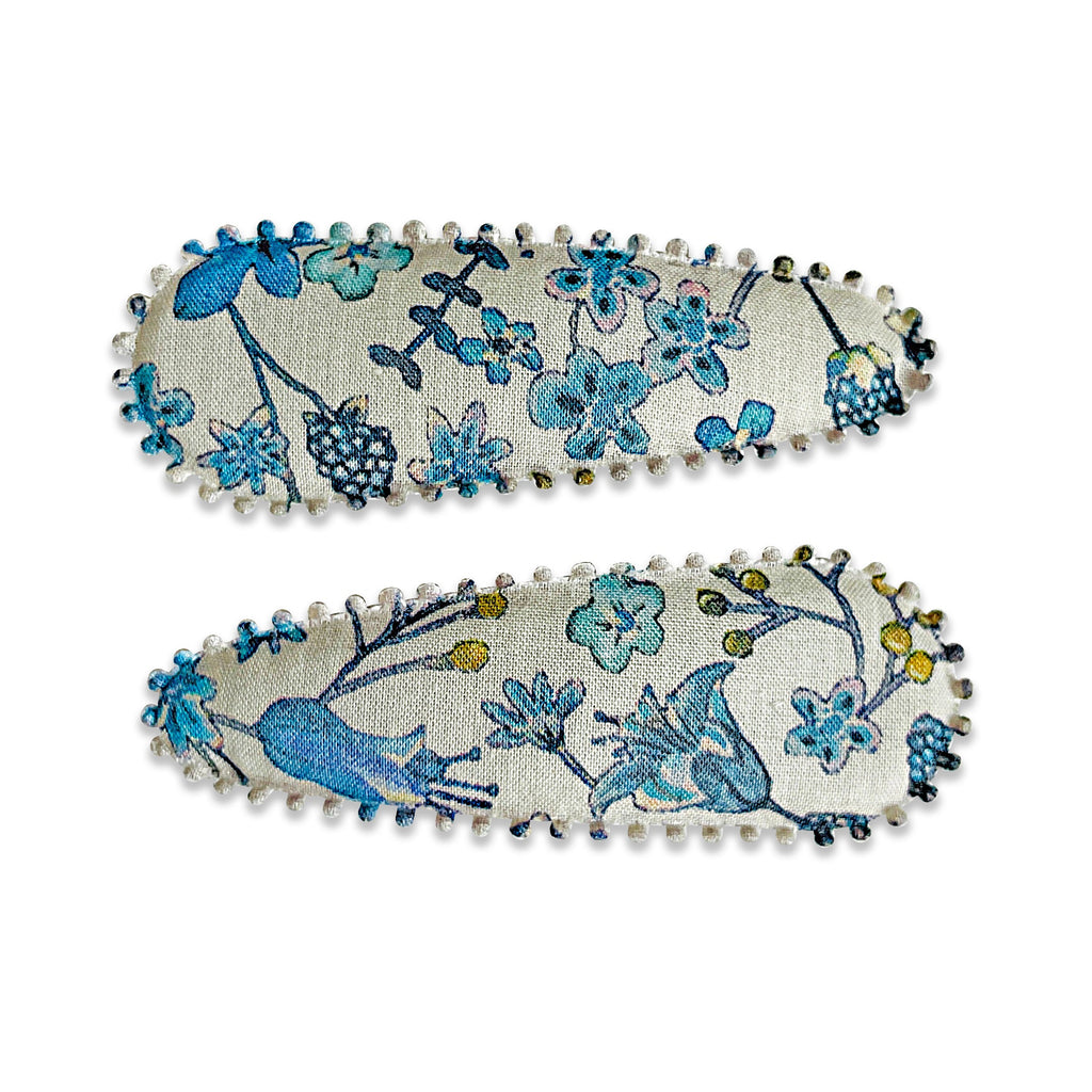 Two fabric-covered snap hair clips with a floral pattern on a light background, featuring scalloped edge detail.