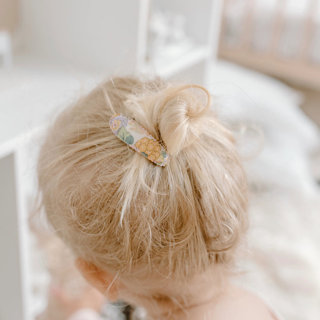 Blonde hair tied up with a decorative clip against a blurred background