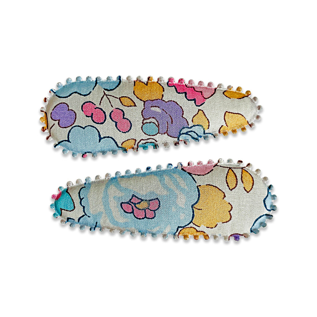 Two fabric-covered snap hair clips with a floral pattern on a light background, sold in a pair.