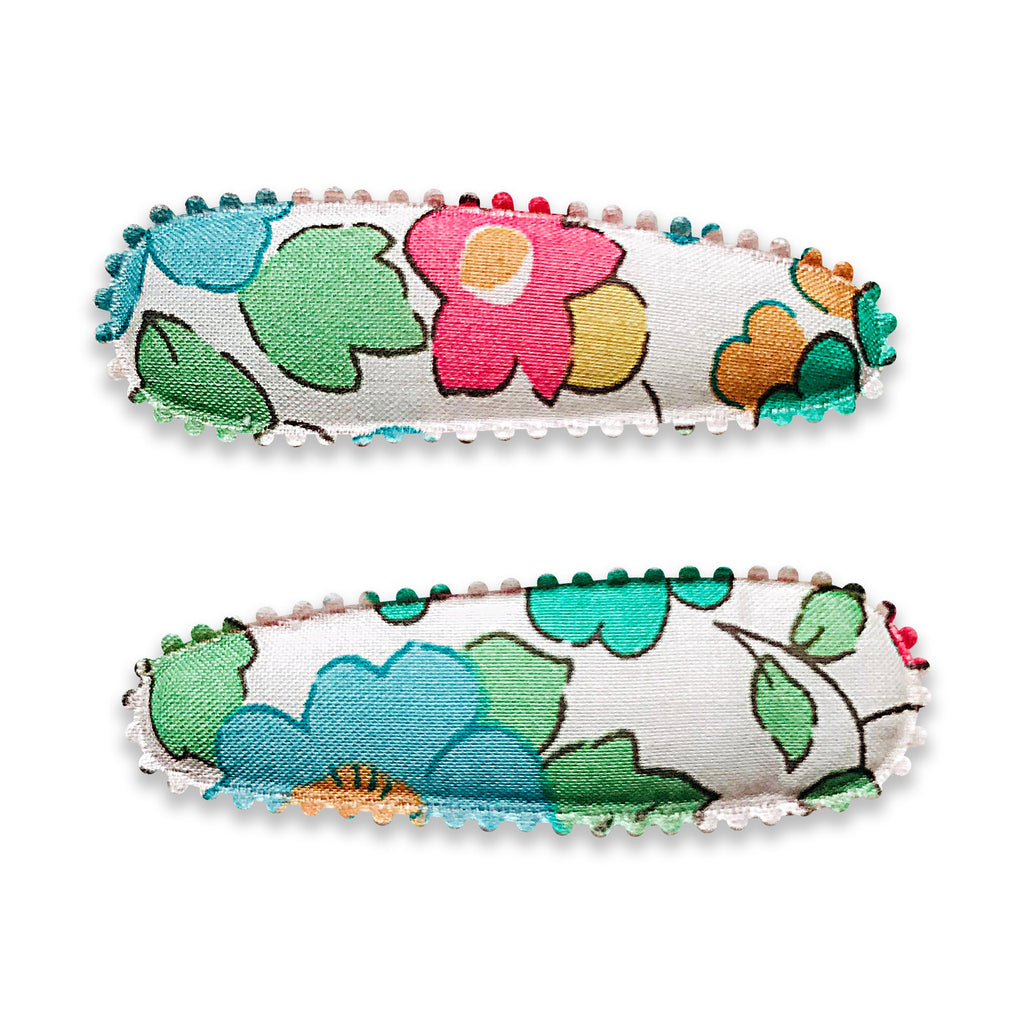 Two fabric-covered snap hair clips with a floral pattern and scalloped edge detail.